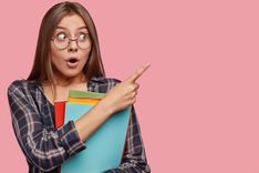 attraktive-junge-geschaftsfrau-die-gegen-die-rosa-wand-mit-brille-aufwirft.jpg